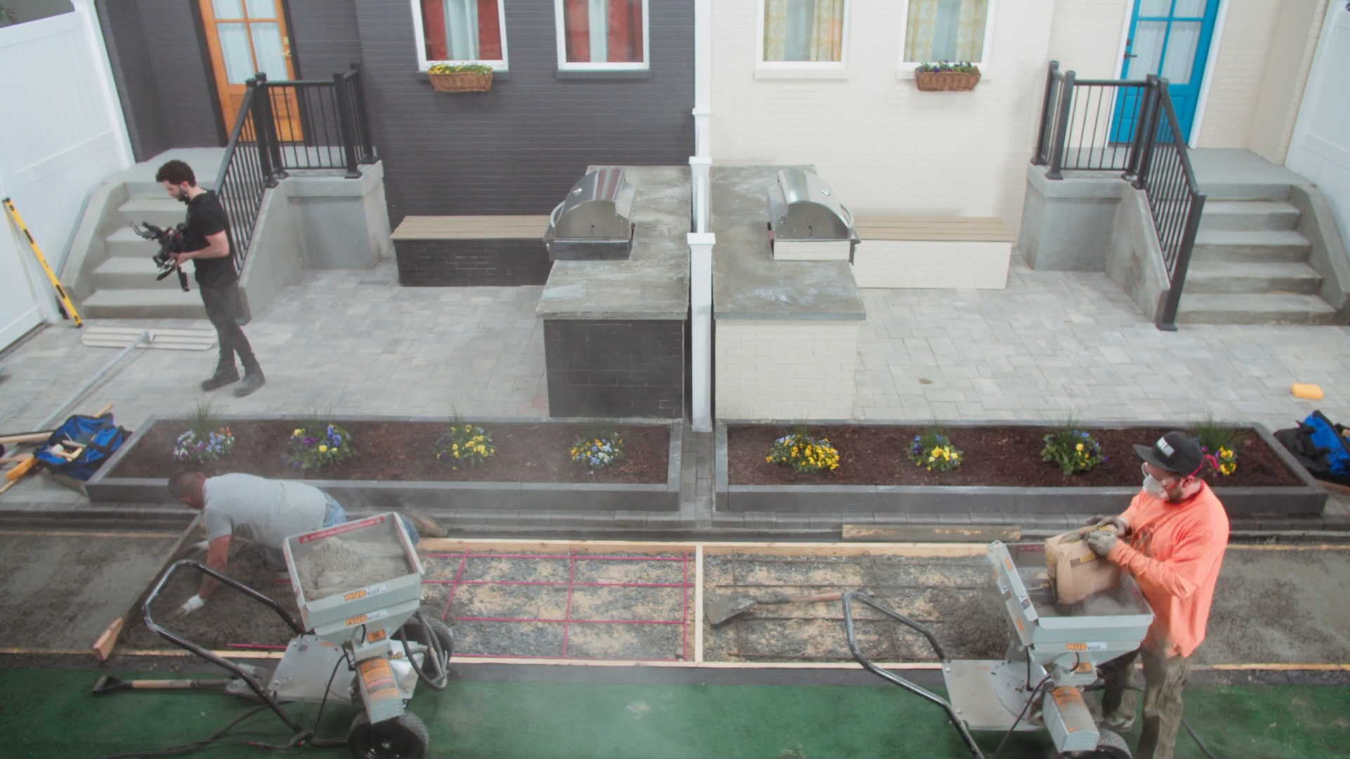 Construction workers installing pavers and landscaping near residential buildings