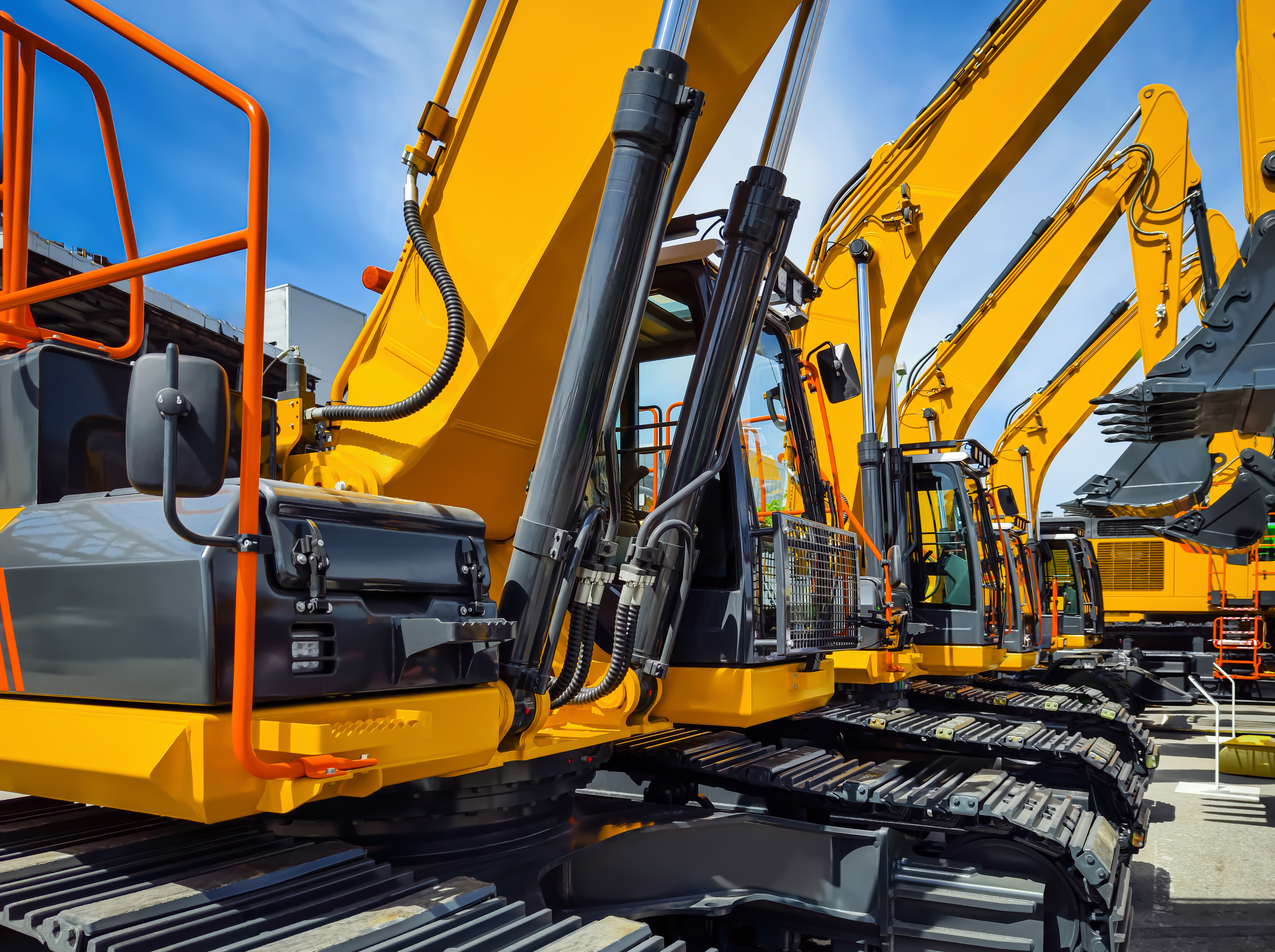 Yellow hydraulic excavators lined up at construction equipment yard