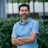 Professional man in blue shirt standing confidently outdoors near greenery Headshot