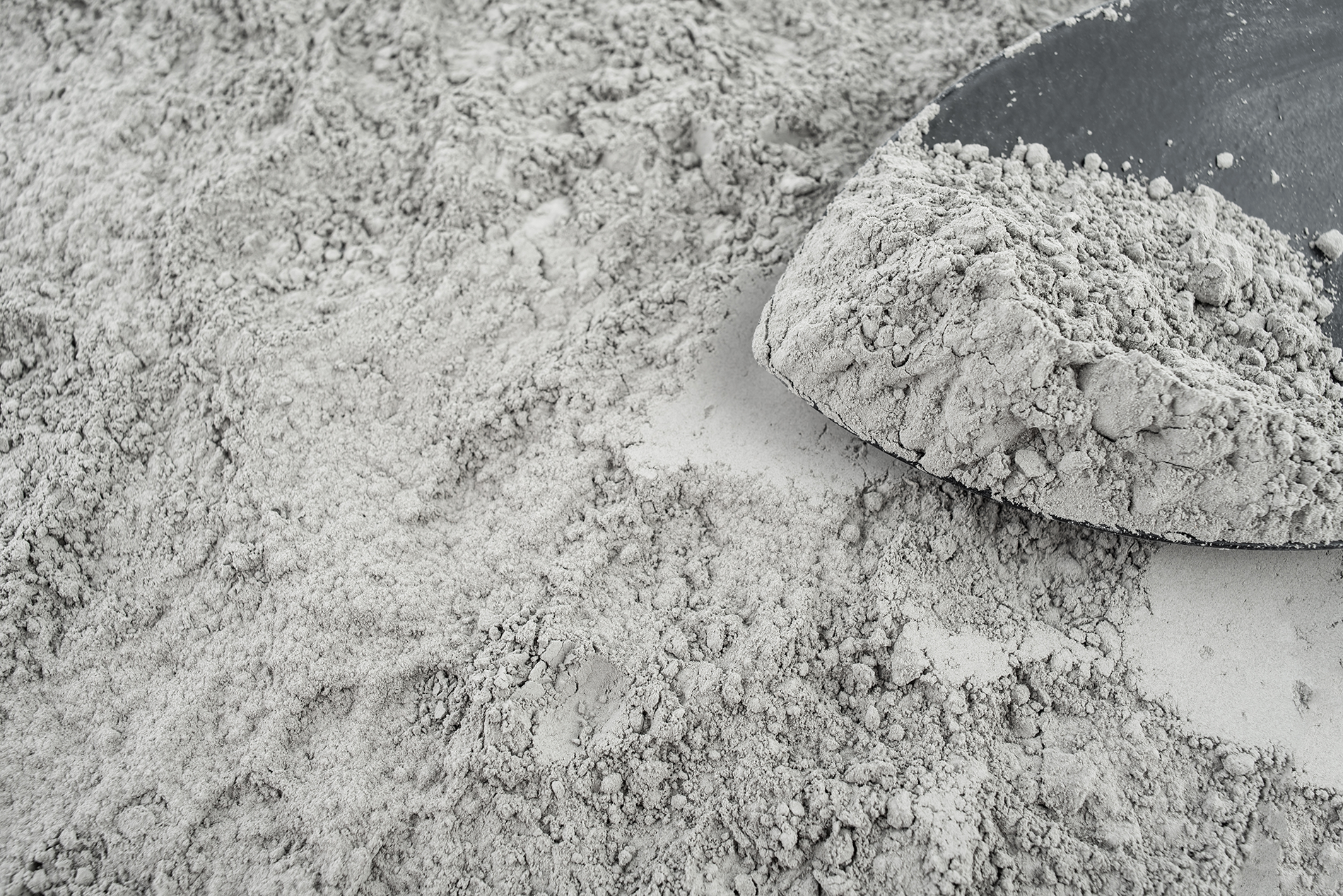 Gray powdery substance spread across surface with mound of dry material