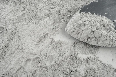 Gray powdery substance spread across surface with mound of dry material