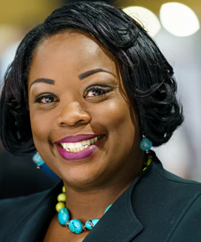 Professional woman smiling, wearing a dark jacket and turquoise jewelry