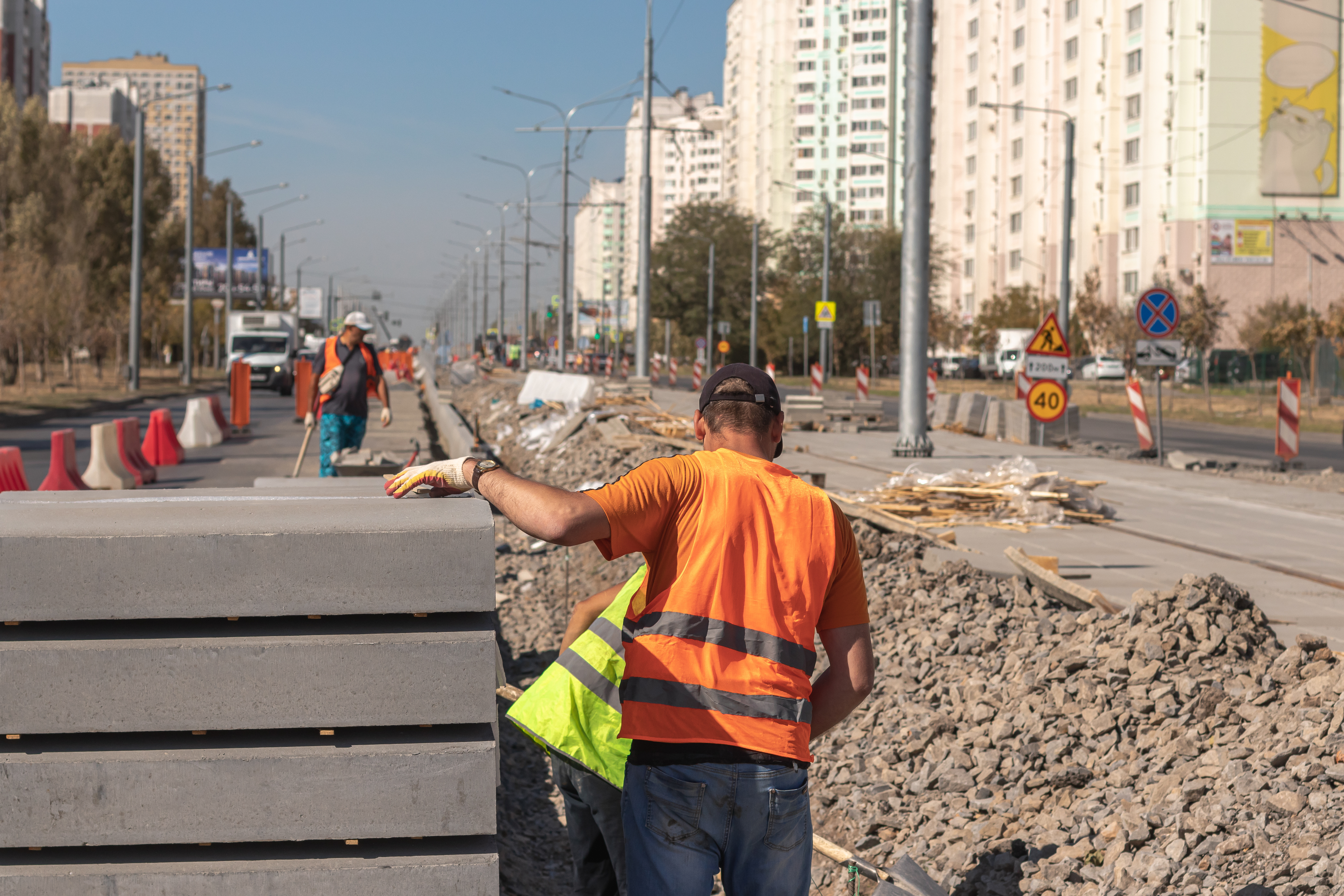 Construction workers in safety vests repairing urban street with road signs