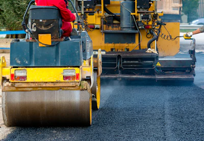 Road roller compacting fresh asphalt during highway construction