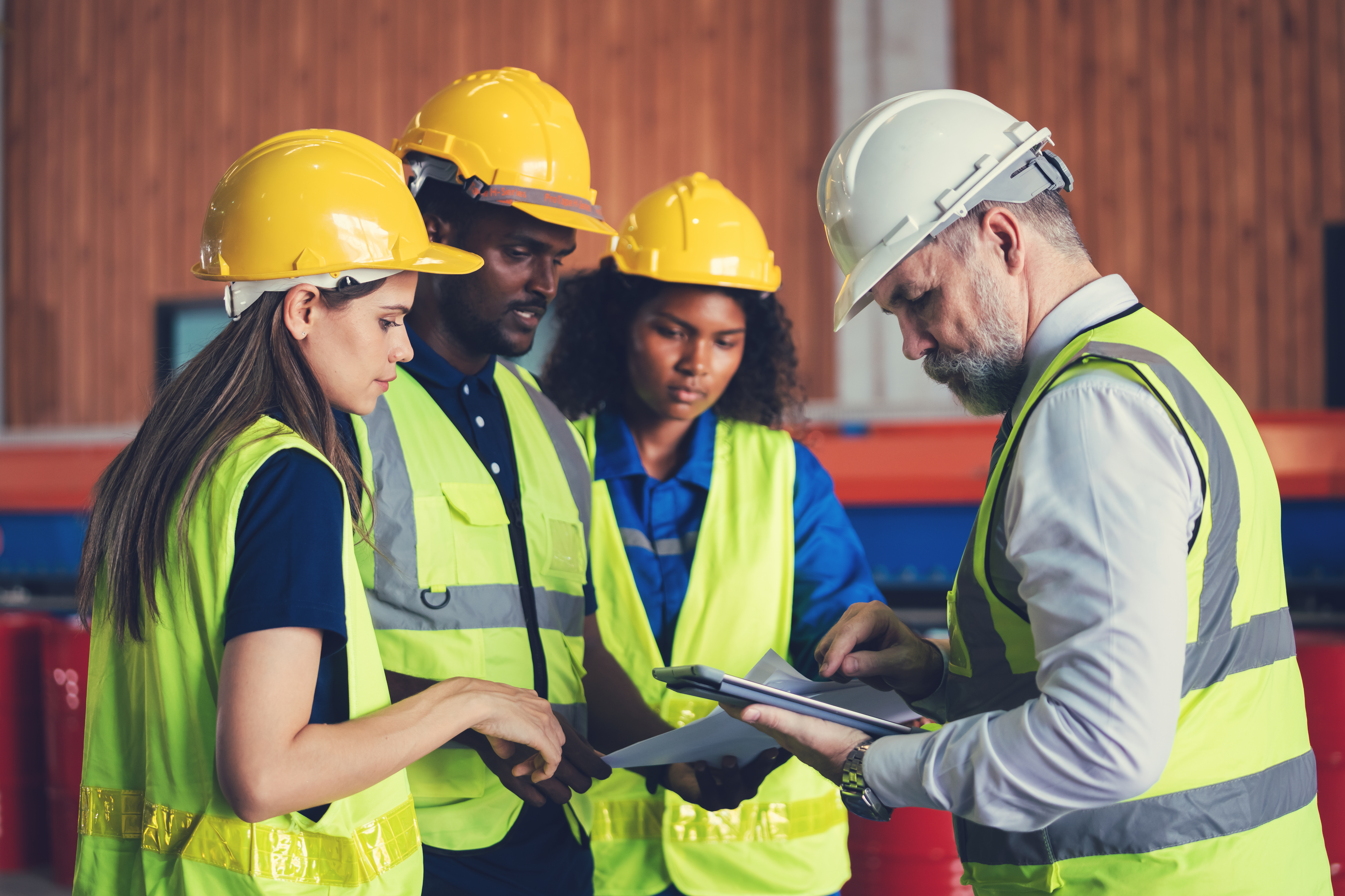 Construction workers in safety vests and hard hats reviewing documents on site