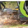 Industrial mulching machine clearing vegetation with wood chips flying