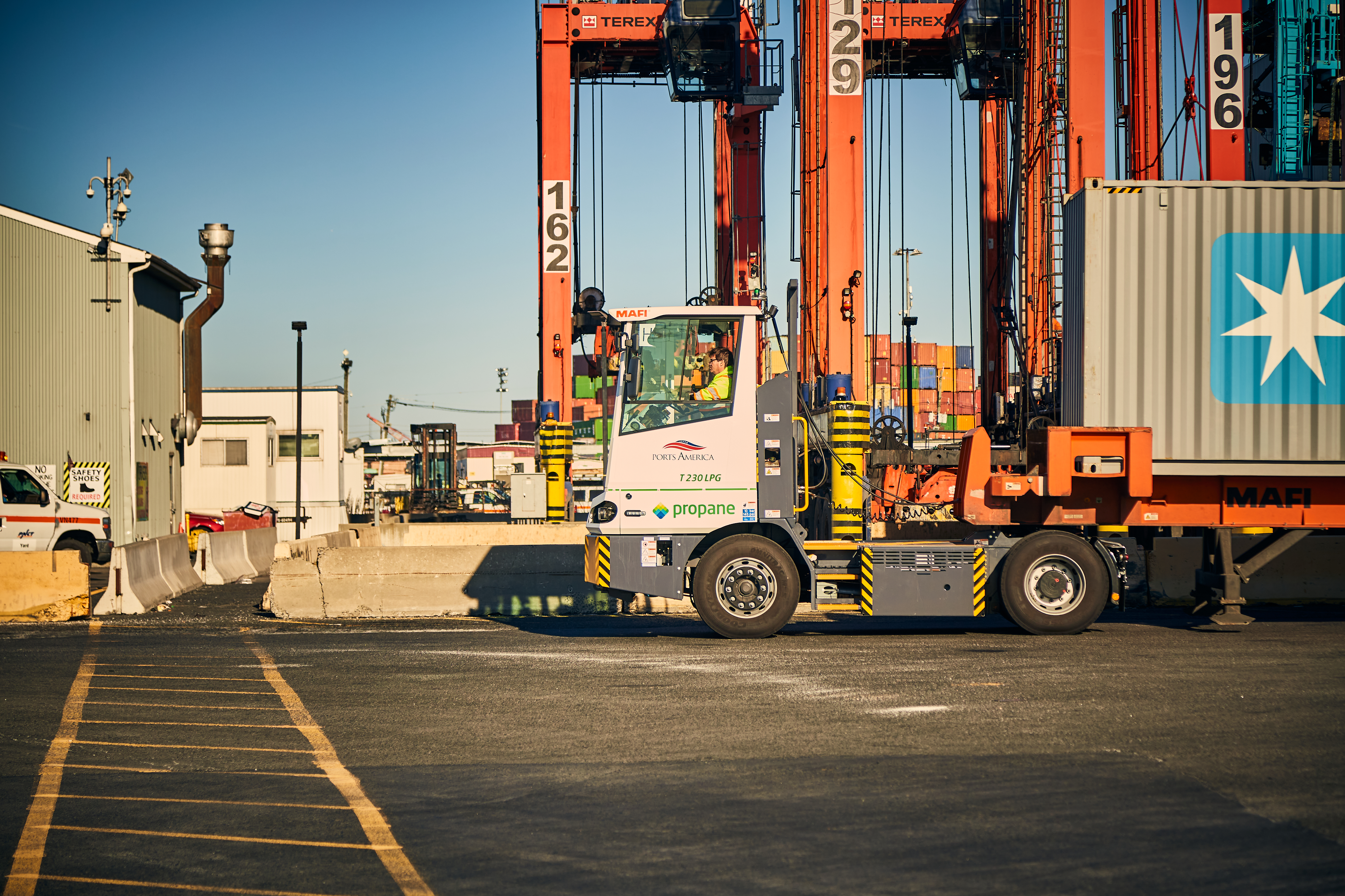 Container port with orange gantry cranes and a terminal tractor moving shipping containers