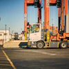 Container port with orange gantry cranes and a terminal tractor moving shipping containers