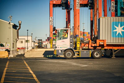 Container port with orange gantry cranes and a terminal tractor moving shipping containers