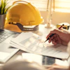Construction professional working at desk with laptop and yellow hard hat