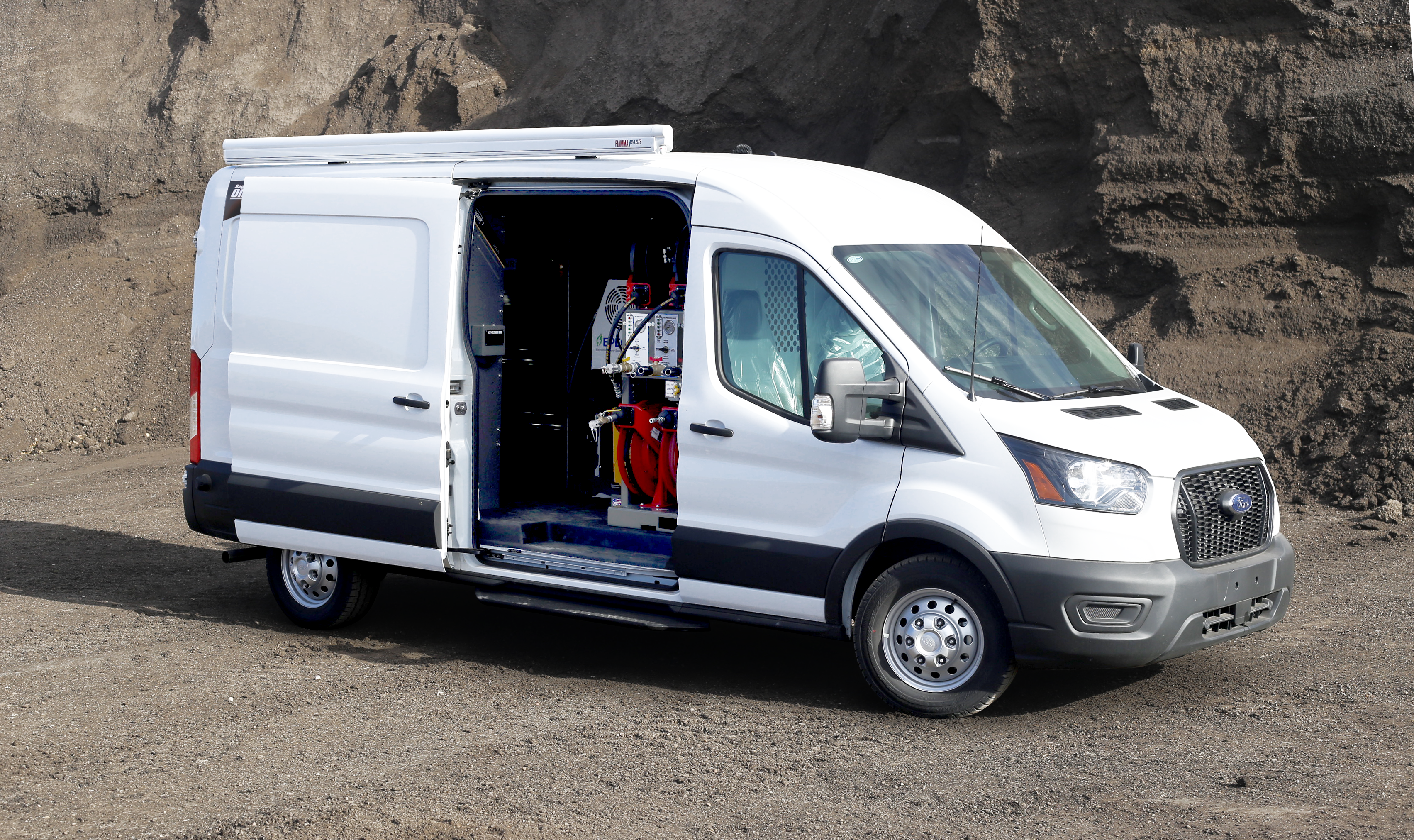 White Ford Transit cargo van with side door open, parked on rocky ground
