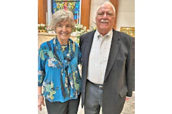 Smiling senior couple dressed formally, standing together in church setting with flowers