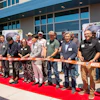 Corporate ribbon-cutting ceremony with diverse group on red carpet outside modern building