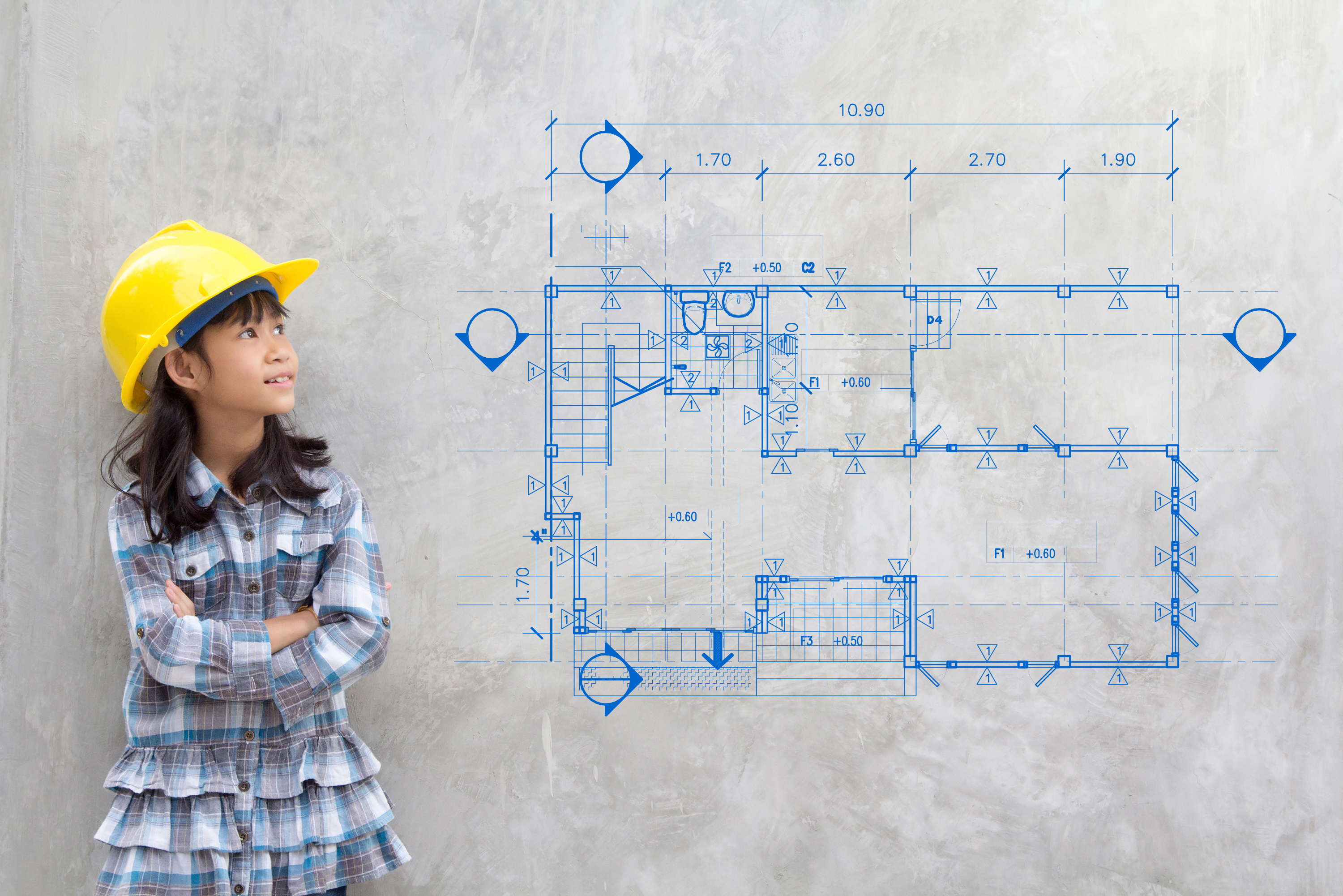 Young engineer in yellow hard hat studying architectural floor plan blueprint