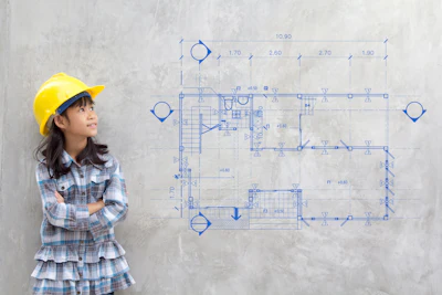 Young engineer in yellow hard hat studying architectural floor plan blueprint