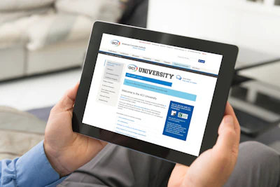 Hands holding tablet displaying ACI University online learning website