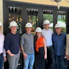 Group of six construction professionals wearing white hard hats standing together