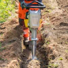 Construction worker operating a Bomag jackhammer to dig a trench in soil
