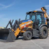 Yellow Case 580 EV backhoe loader on concrete with blue sky background