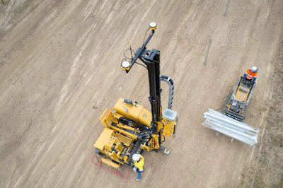 Yellow construction surveying equipment on sandy ground from aerial view