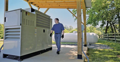 Technician standing near large industrial generator under wooden shelter outdoors