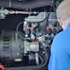 Technician inspecting industrial electrical generator with complex mechanical components