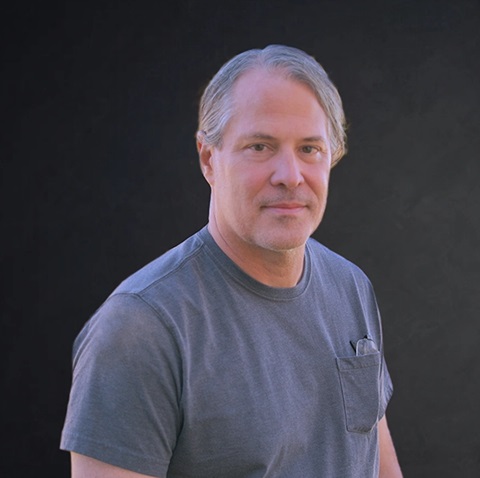 Middle-aged man in gray t-shirt with neutral expression Headshot