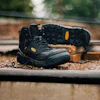 Black Keen work boot with yellow accents on weathered wooden surface