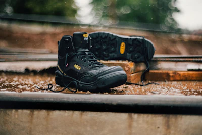 Black Keen work boot with yellow accents on weathered wooden surface