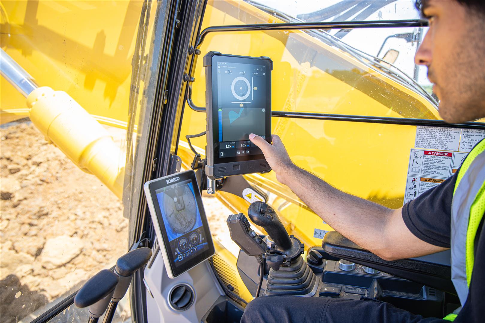 Construction worker operating yellow excavator with digital touchscreen displays