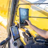 Construction worker operating yellow excavator with digital touchscreen displays