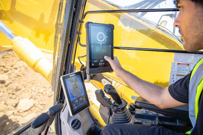 Construction worker operating yellow excavator with digital touchscreen displays