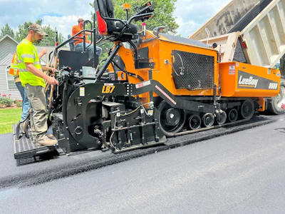 Orange LeeBoy asphalt paver machine laying fresh pavement on residential street