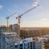 Urban construction site with high-rise buildings and yellow tower cranes at sunset