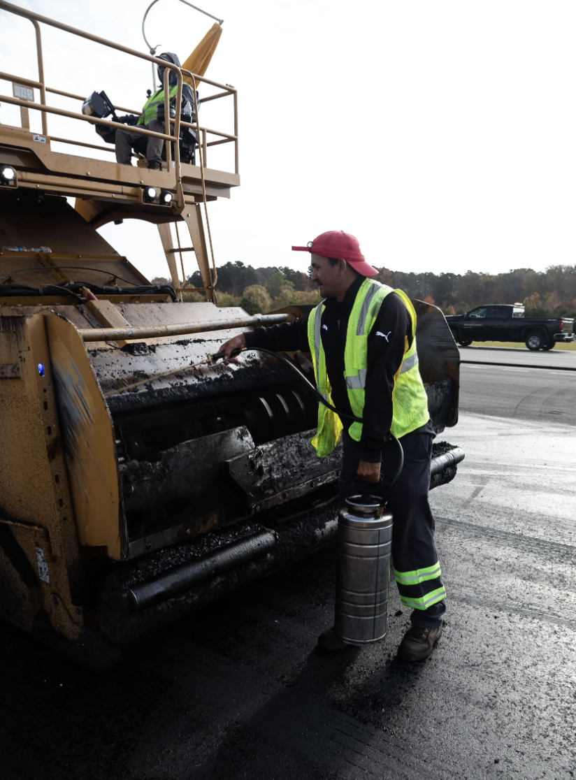 Construction worker operating asphalt paving machine on roadway