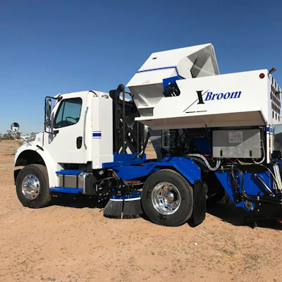 White and blue Xbroom street sweeper truck on dusty desert terrain