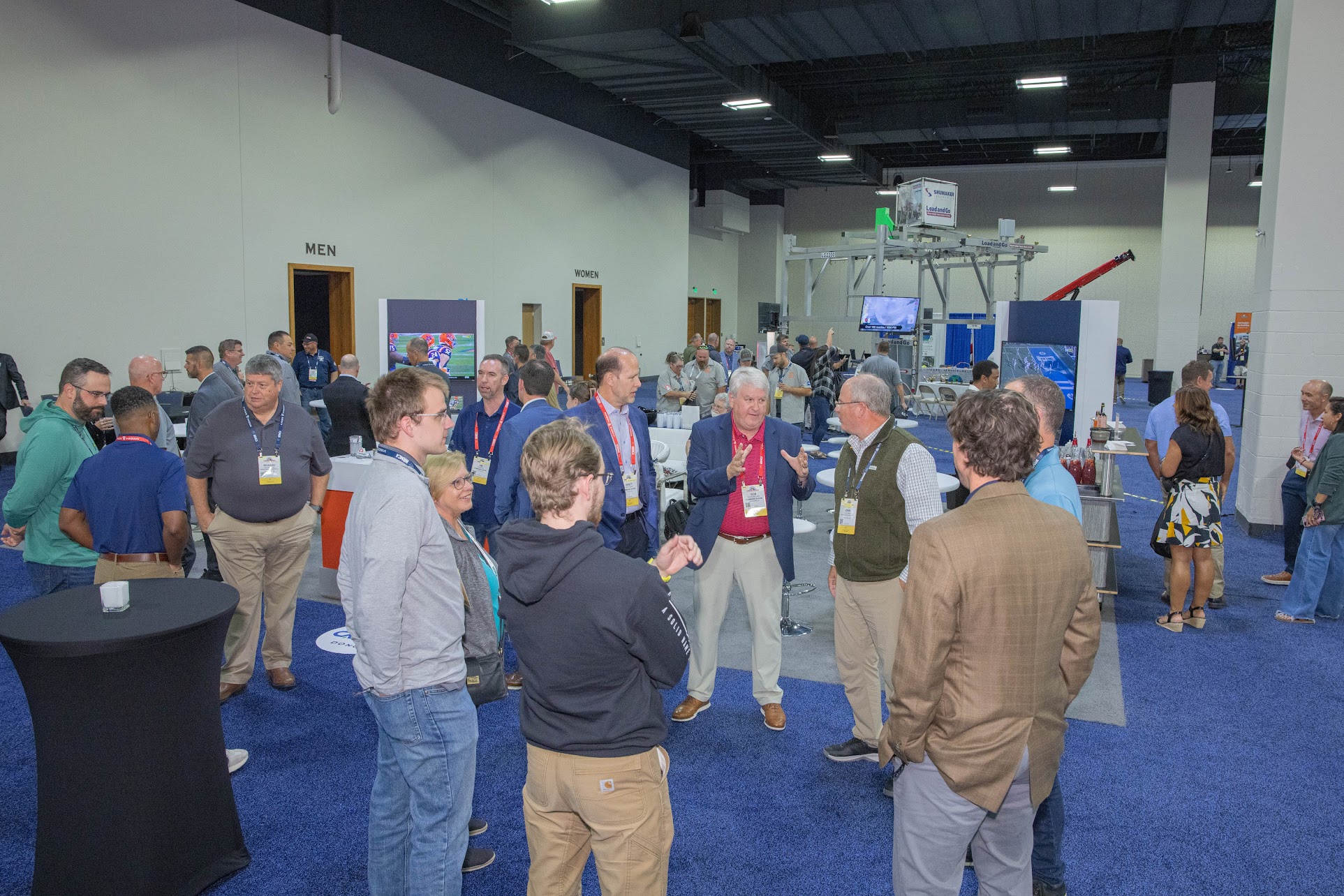 Professional conference attendees networking in blue-carpeted exhibition hall