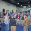 Professional conference attendees networking in blue-carpeted exhibition hall