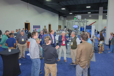 Professional conference attendees networking in blue-carpeted exhibition hall