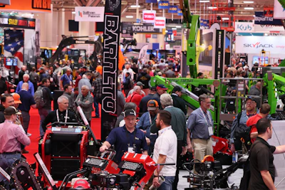 Crowded industrial machinery trade show with red and green equipment displays