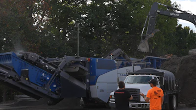 Construction site with blue excavation machinery and workers in orange safety vest