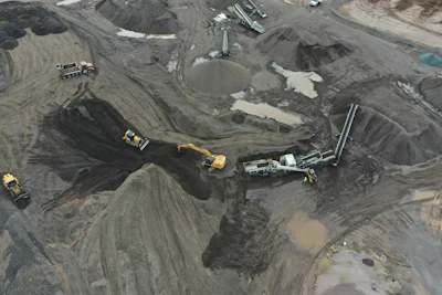 Aerial view of industrial mining site with yellow excavators and gray terrain
