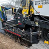 Road construction worker operating Roadtec asphalt paving machine on roadside