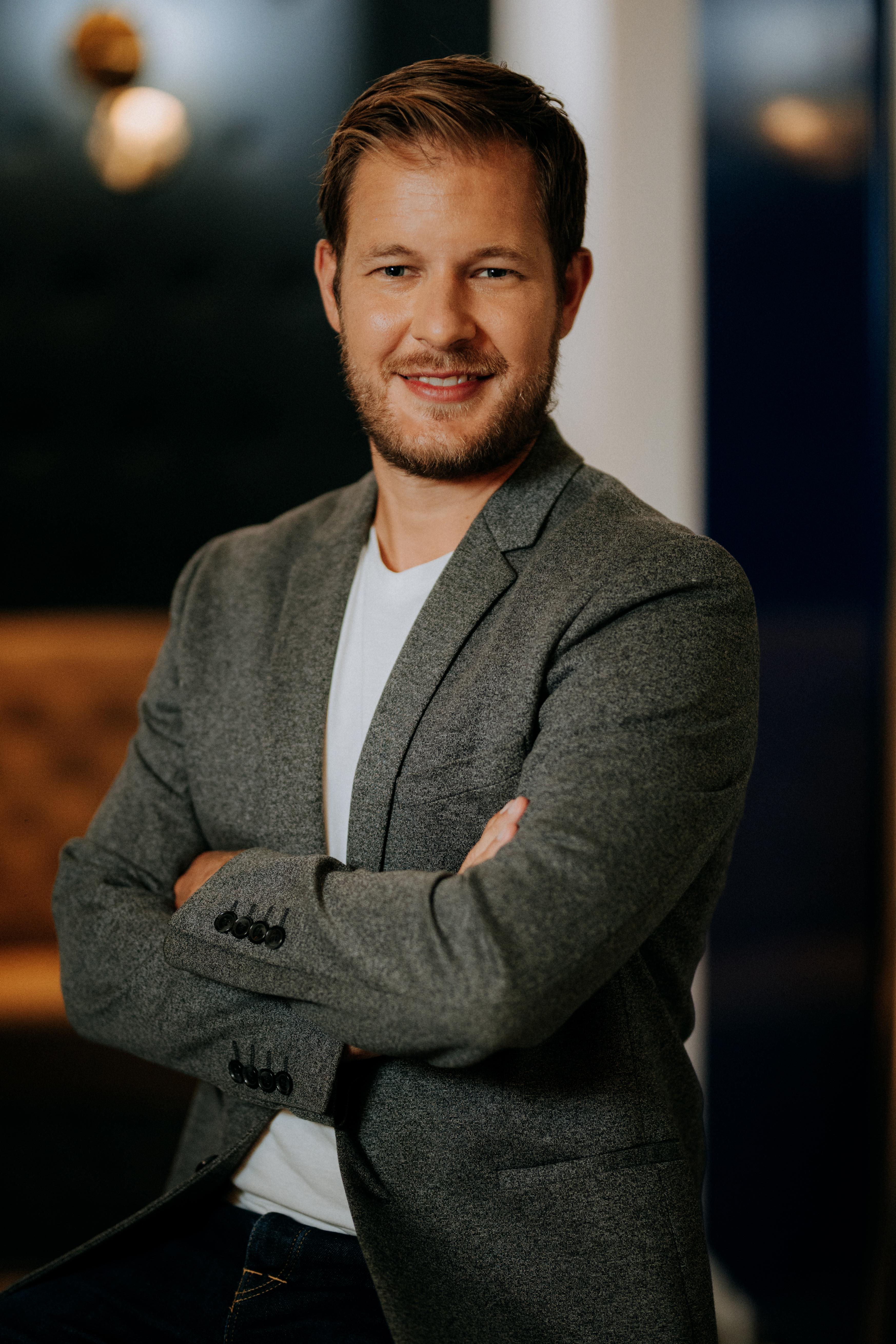 Professional man in gray blazer smiling with confident pose Headshot