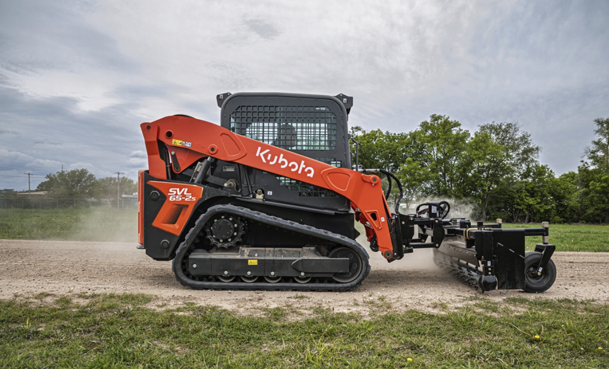 Orange Kubota SVL skid steer loader with attachment on dirt ground