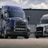 Two Mack semi-trucks parked side by side in industrial loading area