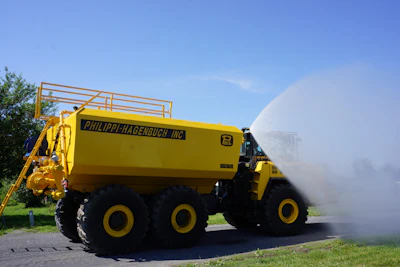 Large yellow industrial water truck by Philippi-Hagenbuch spraying water on pavement