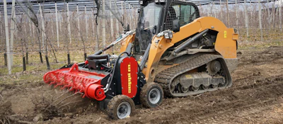 Yellow tracked skid steer with red forestry mulcher working in bare orchard