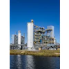 Industrial chemical processing plant with white tanks and metal structures near water