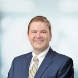 Smiling professional in navy blue suit and striped tie against blurred background